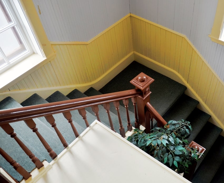staircase with green carpet and yellow and white walls