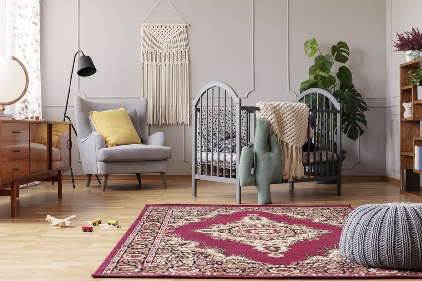 Stylish nursery with vintage furniture and red rustic rug