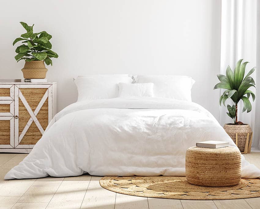 White cozy farmhouse bedroom interior with white comforter jute rug