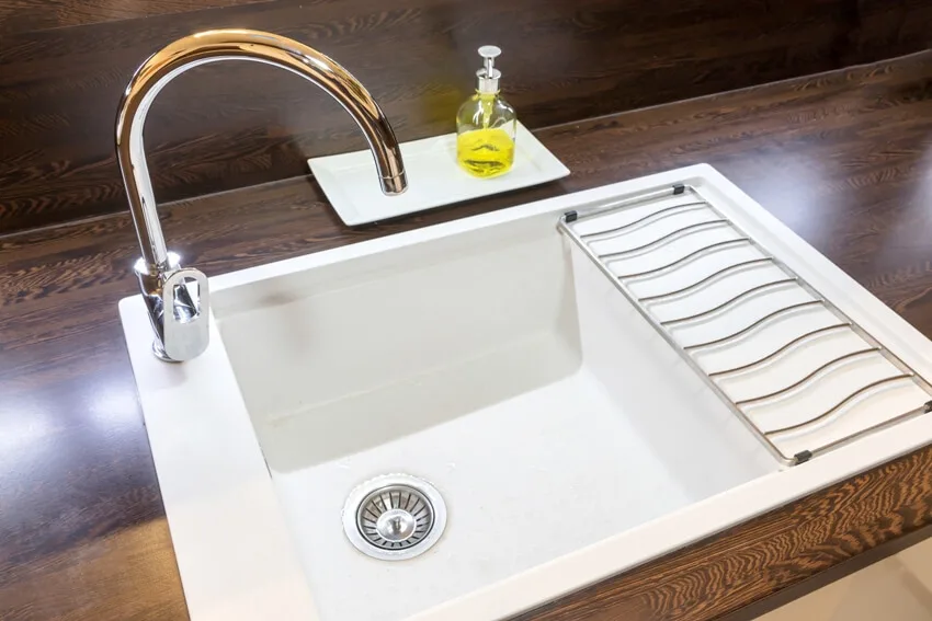 A white empty kitchen cast iron sink with liquid soap