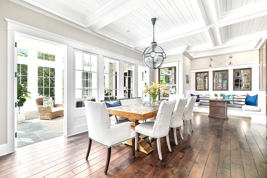 white paint coffered ceiling with bench dining and spacious area next to bright and cheery sunroom
