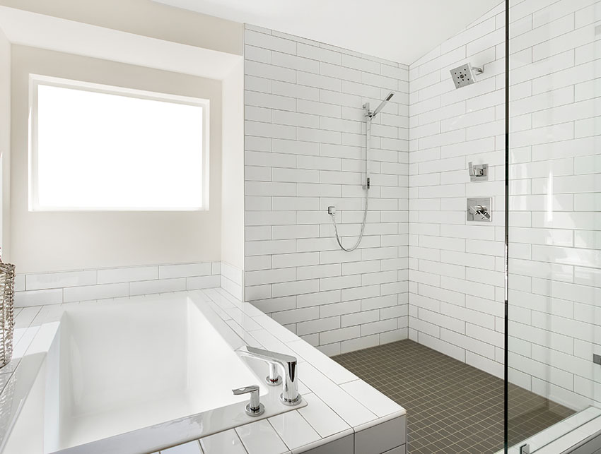 Shower area with tub and stainless spread fit faucet white tiles is