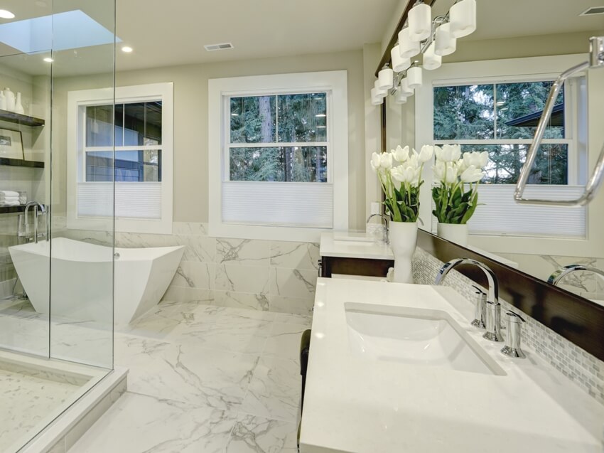 Amazing white and gray marble master bathroom with large glass walk in shower, freestanding tub and skylights on the ceiling