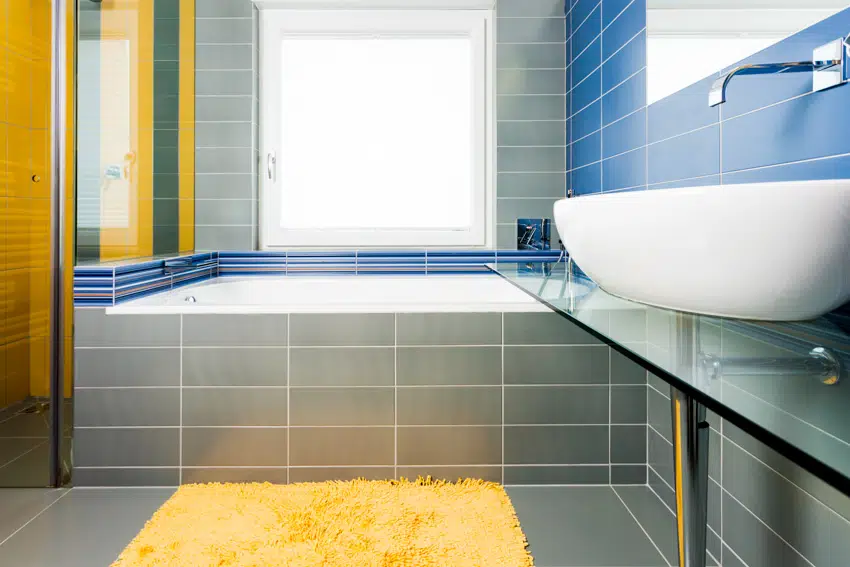 Bathroom with gray tiles basin sink glass divider rug