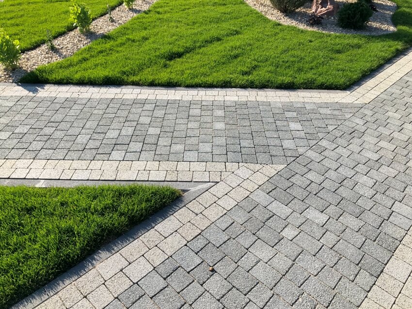 Beautiful garden nested with cobblestone pavers surrounded with green grass