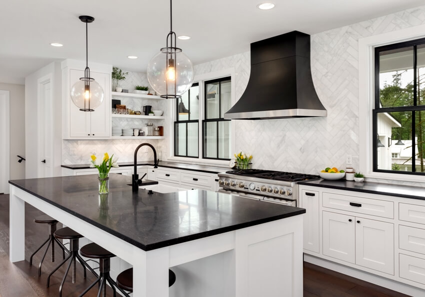 Kitchen with black counters and island with white woodwork and cabinetry