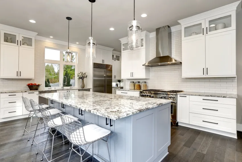 A beautiful kitchen with double stacked cabinets island and stainless steel chairs