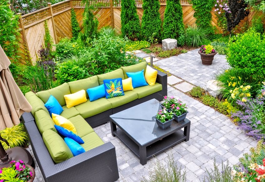 A beautiful small urban backyard garden featuring a tumbled paver patio with a variety of trees and shrubs