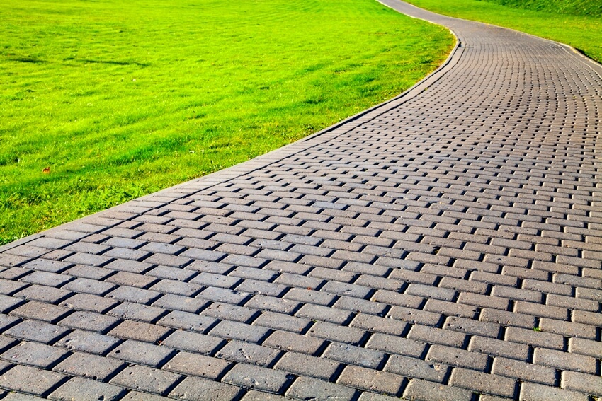 Beautiful summer city park walkway with cobblestone path and green lawn