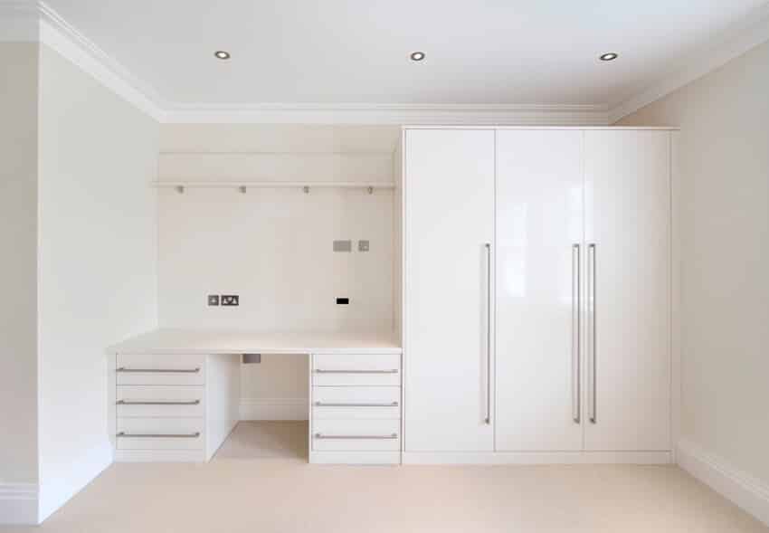 A bedroom with white walk in closet and a desk 