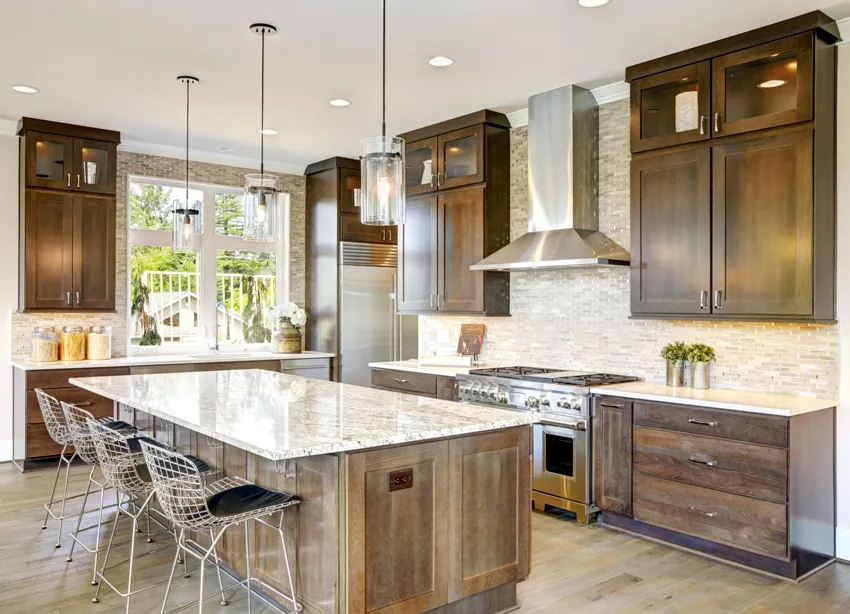 A classic kitchen interior with wooden cabinets island with chairs and marble countertop