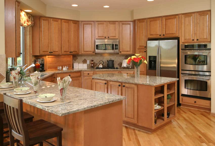 Classic kitchen space with light maple cabinets wood flooring center island dining area