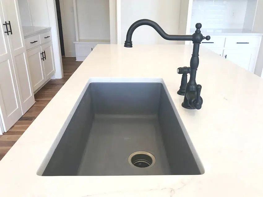 Close up of gray farmhouse kitchen sink with quartz countertop