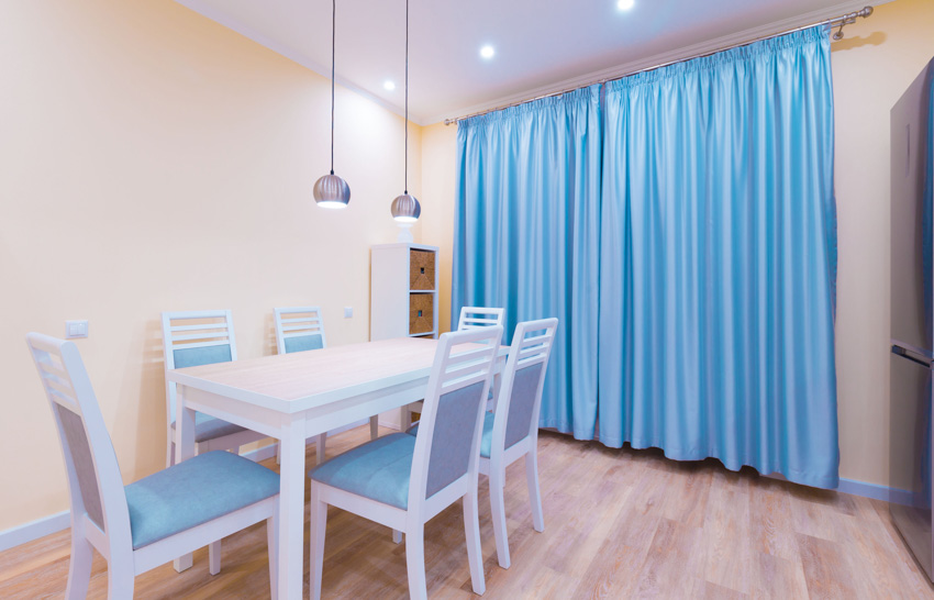 Dining room with yellow wall hanging light teal curtain