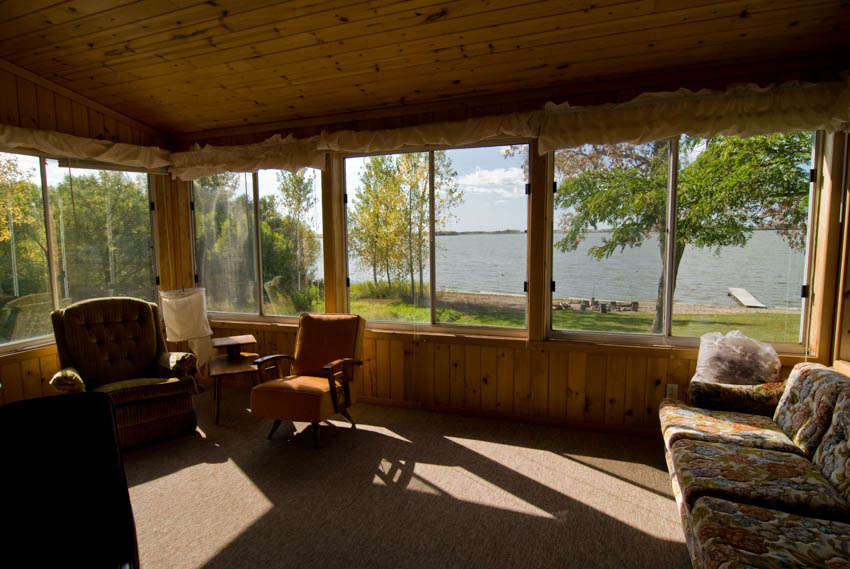 Enclosed porch with sofa chairs wood ceiling and windows