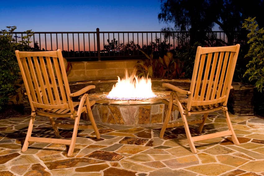 Fire pit burning at night lounge chairs patio tiles