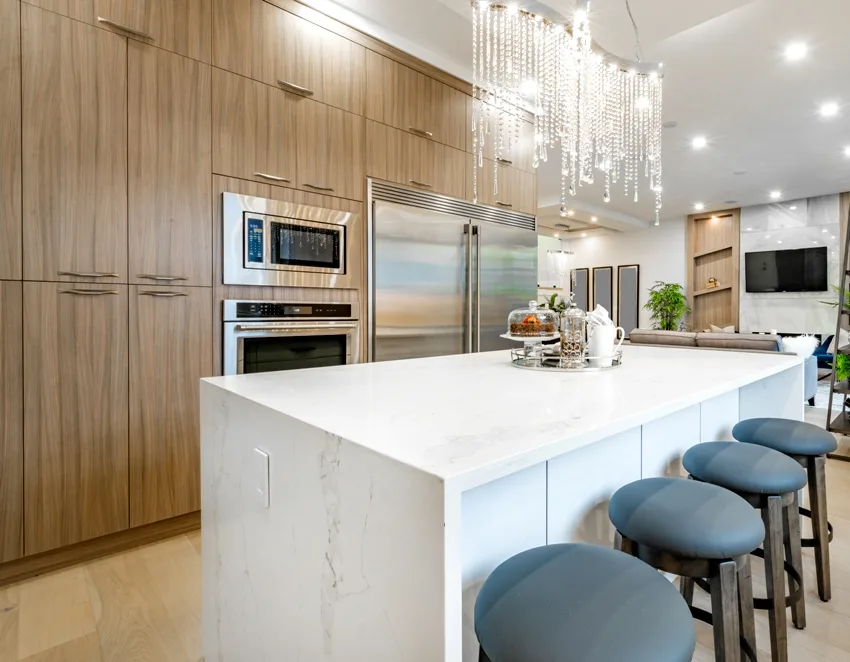 Gorgeous kitchen with wooden cabinets and white kitchen island with chairs and marble countertop
