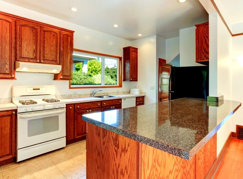 Kitchen interior with tile floor dark wooden cabinets with granite tops and white appliances