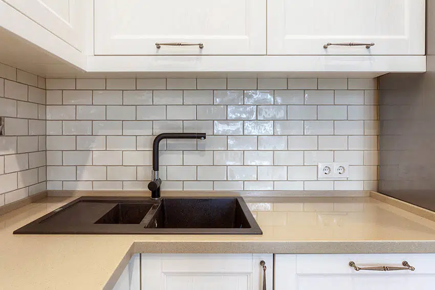 Kitchen with tile backsplash white cabinets and quartz style sink 