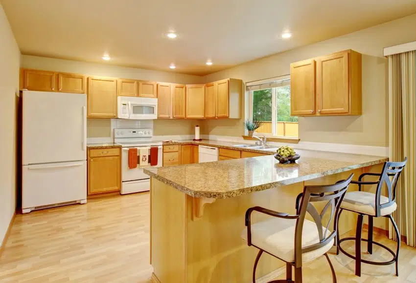 Kitchen with yellow lighting white appliances and maple cabinets