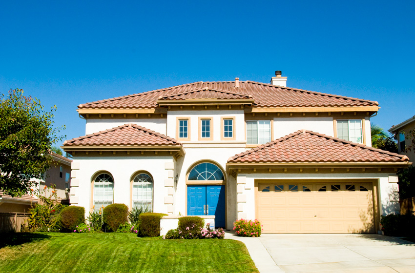 Large house spanish style front lawn blue exterior door garage