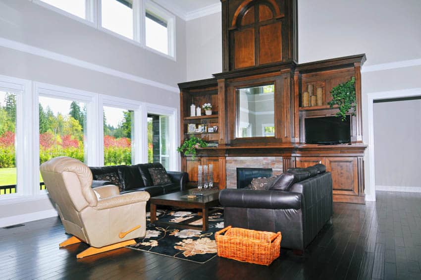 Living room with sofa chairs, white glider recliner, glass windows, and black floor