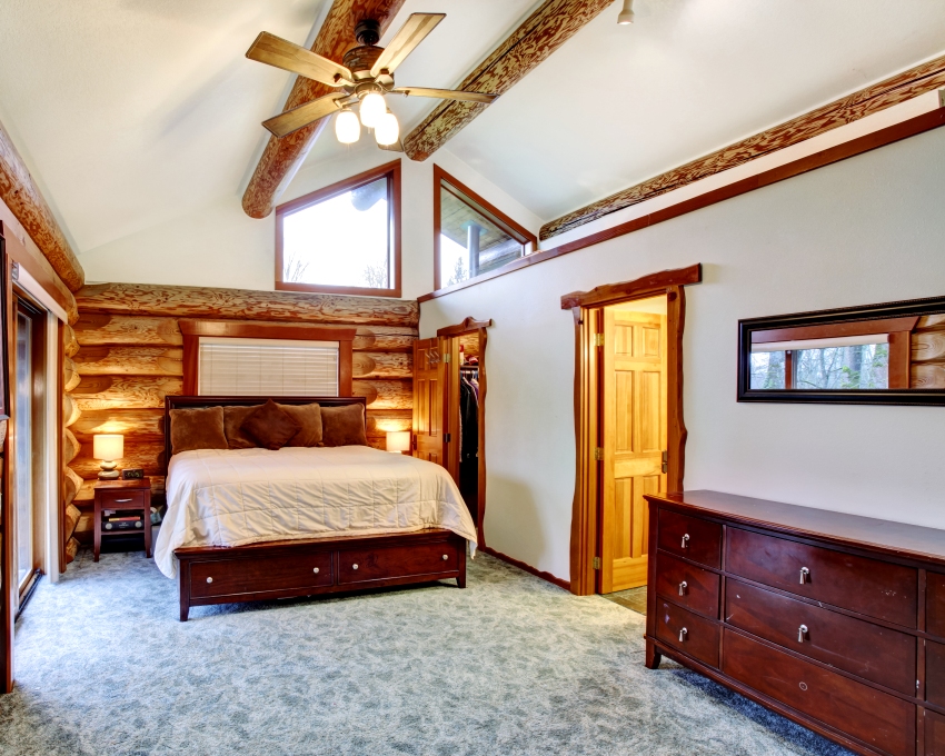 Log cabin bedroom under pitched ceiling with cherrywood furniture set