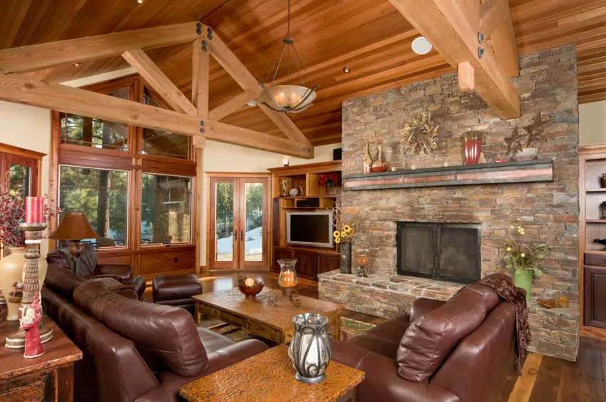 cabin brown leather furniture fireplace wood stained floor and arched ceiling