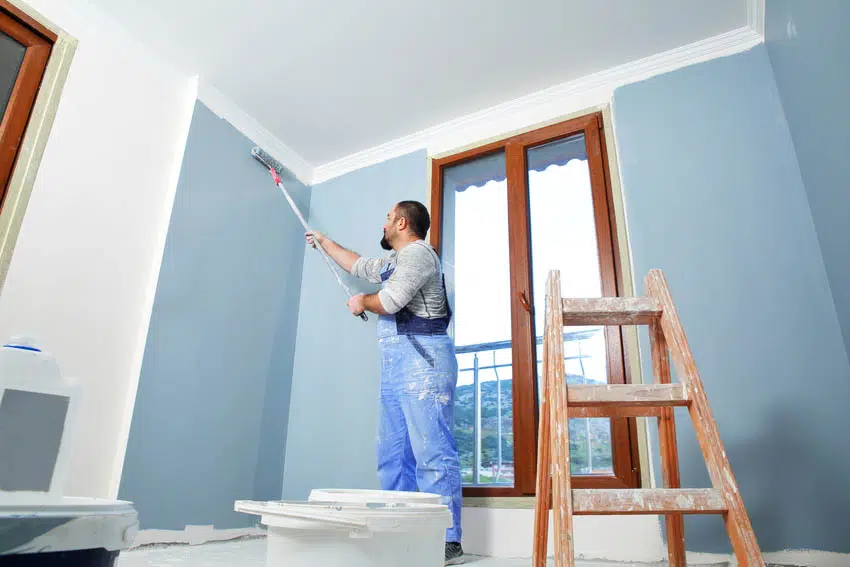Man painting room with light blue paint