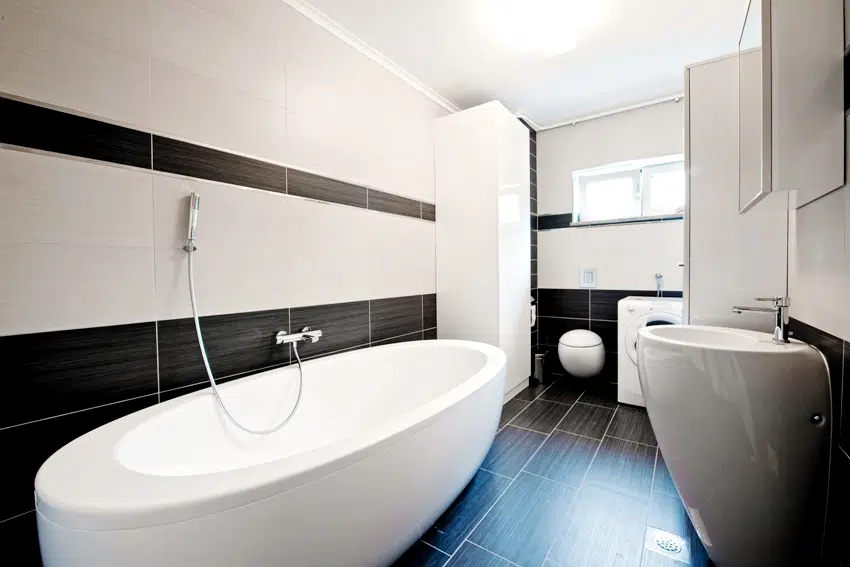 A modern bathroom with black and white tiles and bathtub 