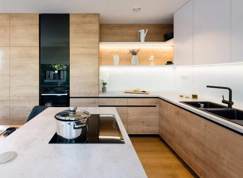 Modern kitchen interior with wood and black accents and an island with stove top and pot on it