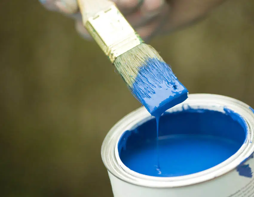 Opened can of blue paint with paint brush