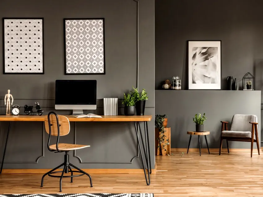 Patterned framed posters on the wall above desk with computer monitor in grey home office interior