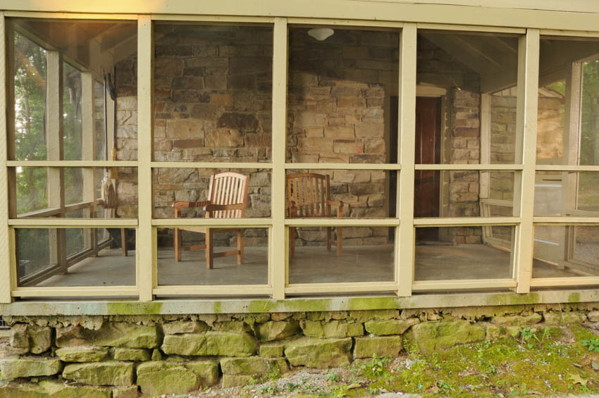 Porch transformed into a room with chairs brick wall tall glass windows