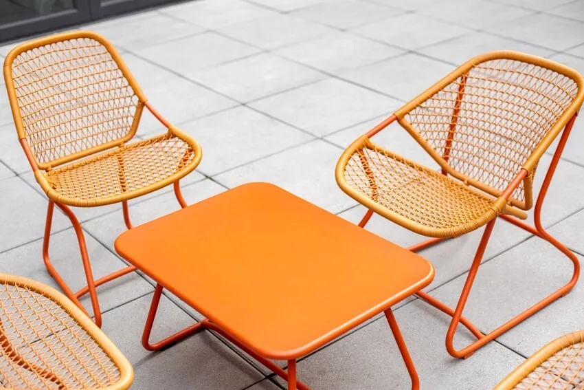 Set of orange painted patio furniture around a metal coffee table