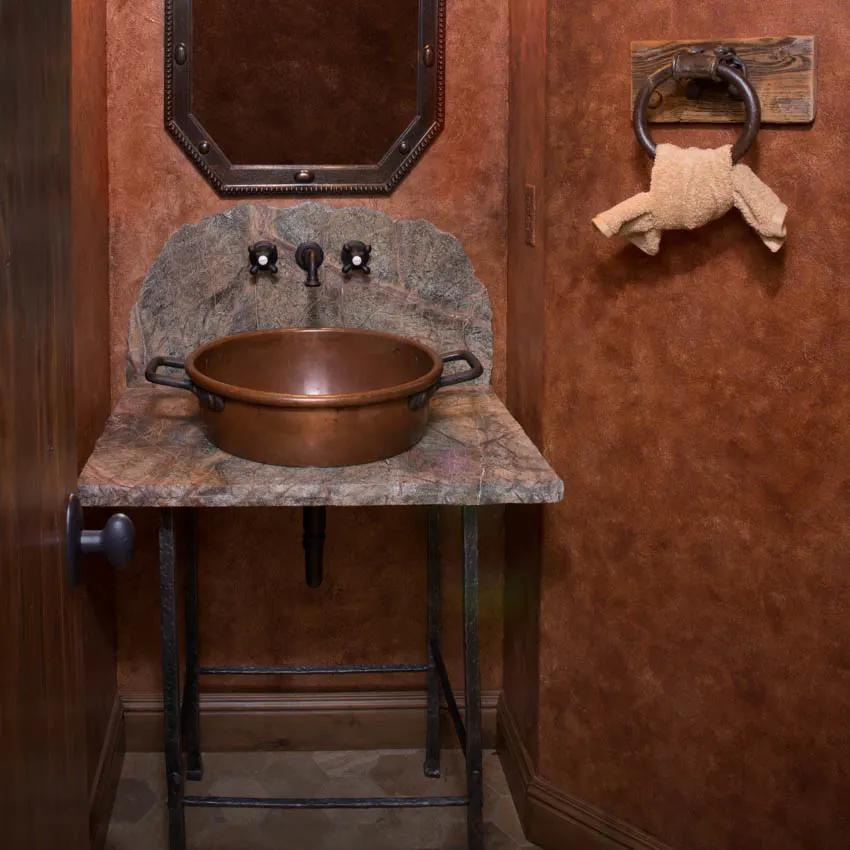 Small bathroom space with rustic copper sink mirror and red wall