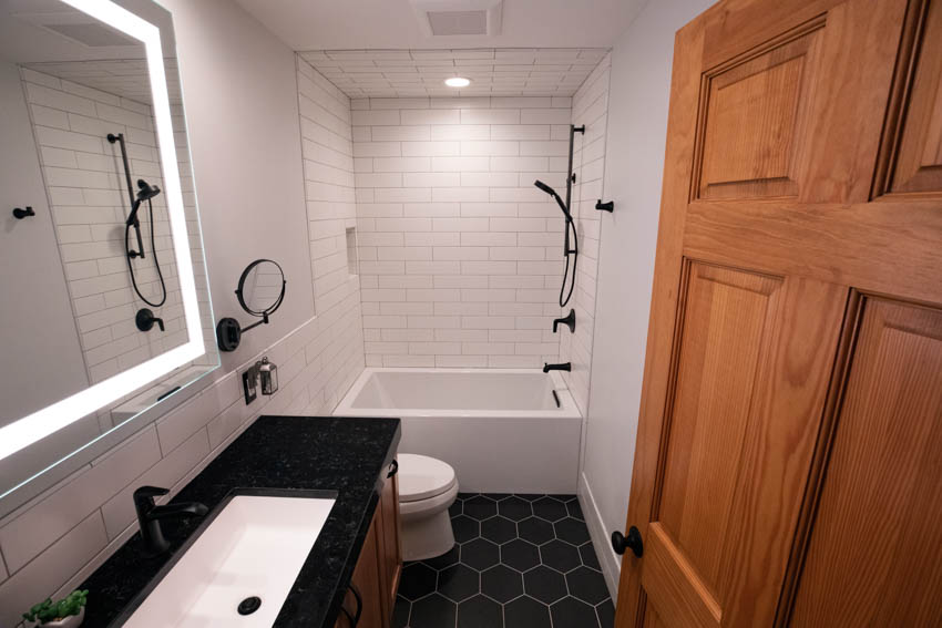 Small bathroom with tub wood door tile floor mirror shower toilet