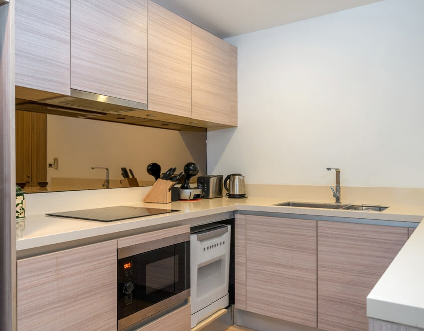 A small kitchen interior with laminate handleless cabinets and appliances