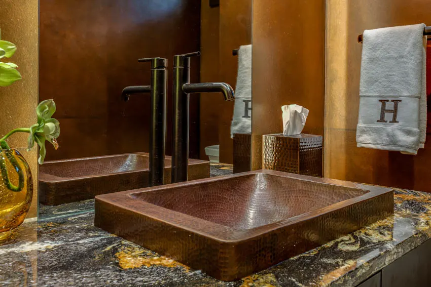 Square shaped copper sink on marble countertop