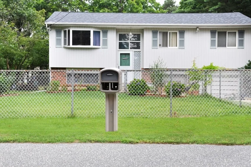 Suburban residential high ranch style home with chain link fence with curbside mailbox