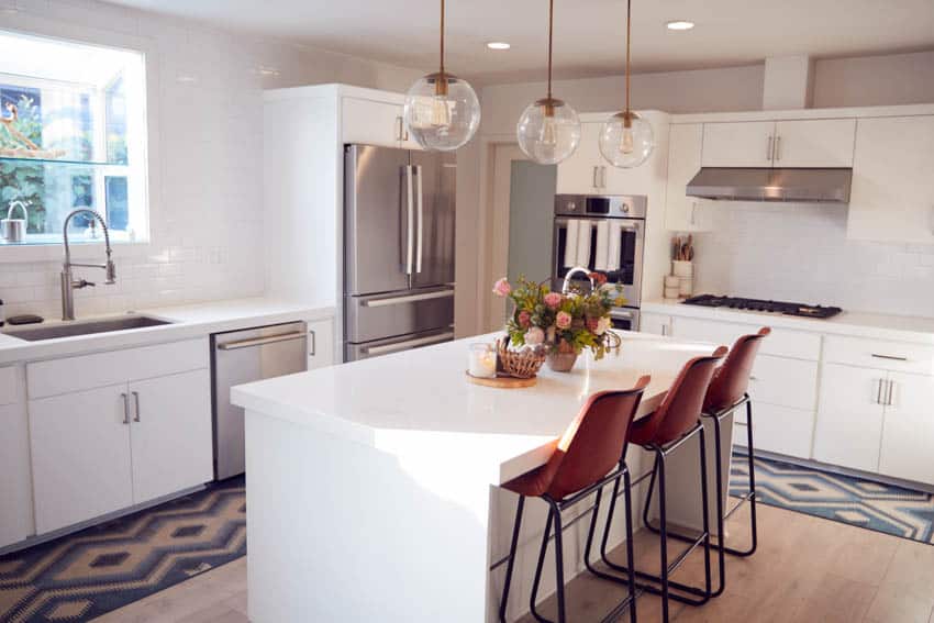 White kitchen island with centerpiece red chairs hanging lighting