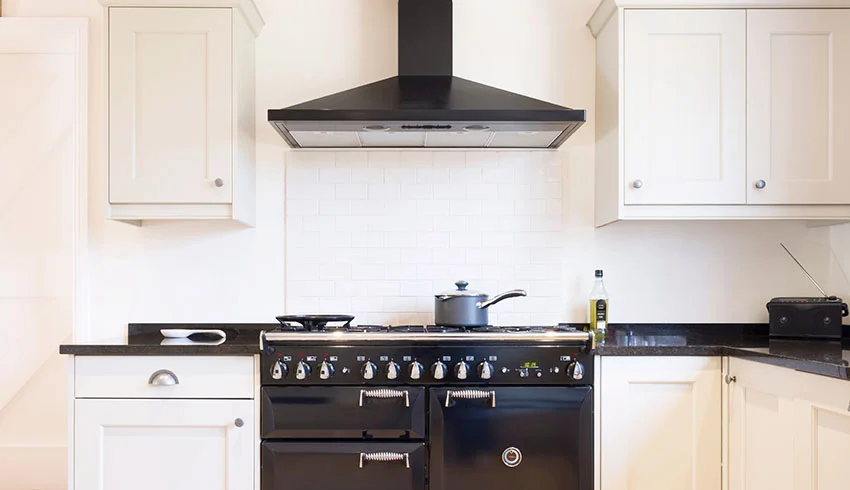 Kitchen with white cabinets black countertop range hood