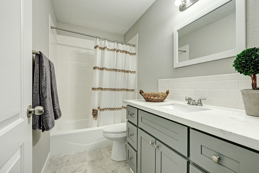 Bathroom interior boasts silver grey vanity cabinet topped with marble counter top and white backsplash