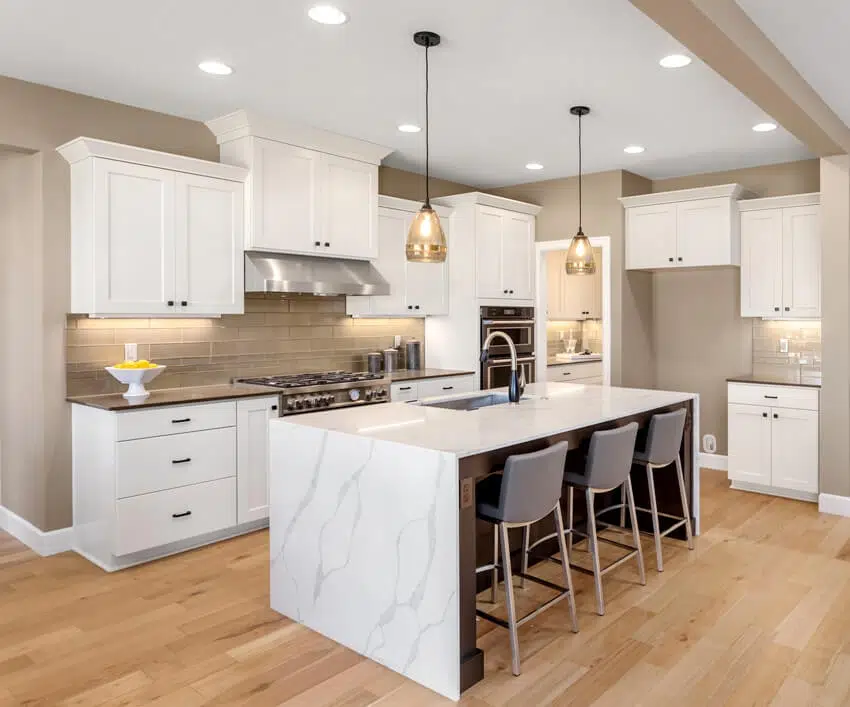 Beautiful kitchen in new home with waterfall island pendant lights and hardwood floors is