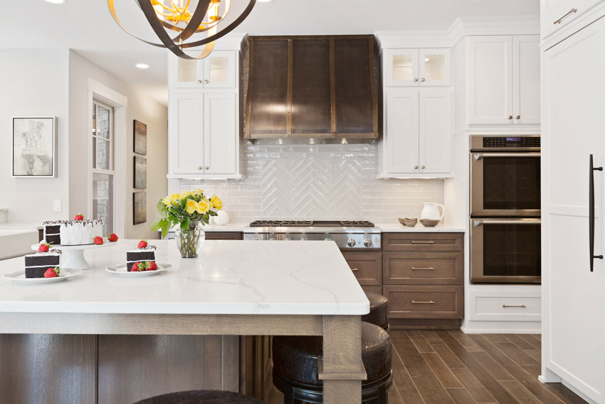 Beautiful kitchen with glass herringbone backsplash hood wood floors center island countertop oven