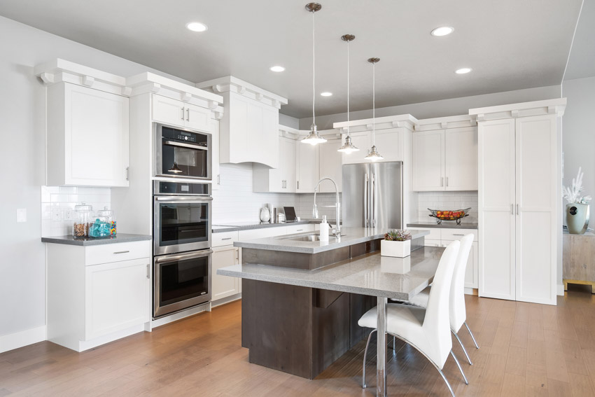 Beautiful kitchen with wood flooring floating center island white cabinets oven hanging lights