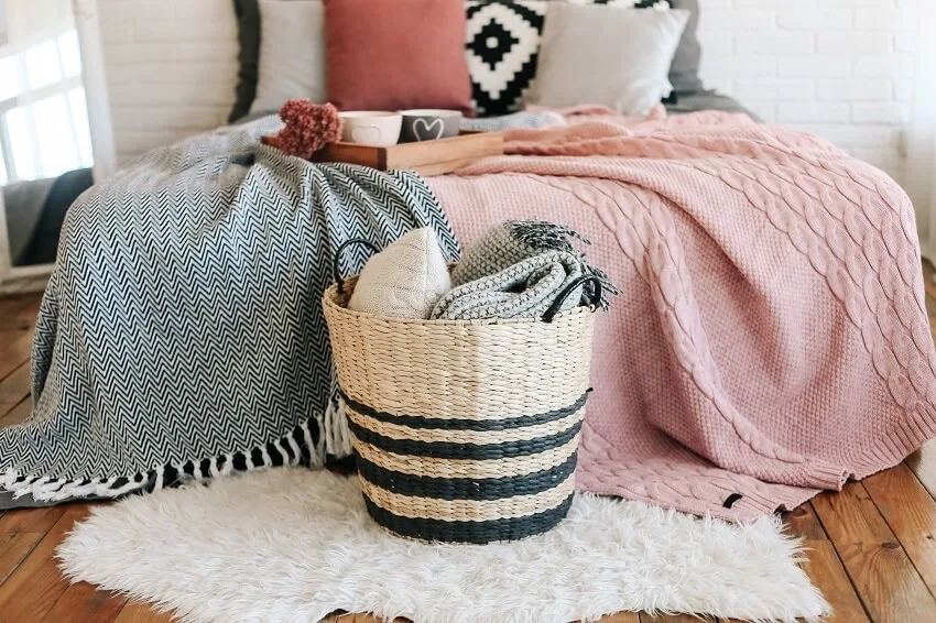 Bedroom interior a basket with blankets stands near the bed on a carpet of fur