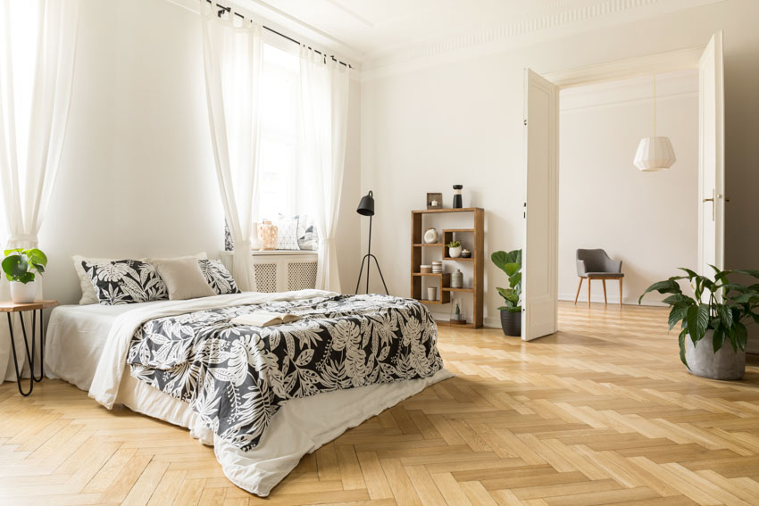 Bedroom with prefinished herringbone wood floor, glass windows, curtains and indoor plants