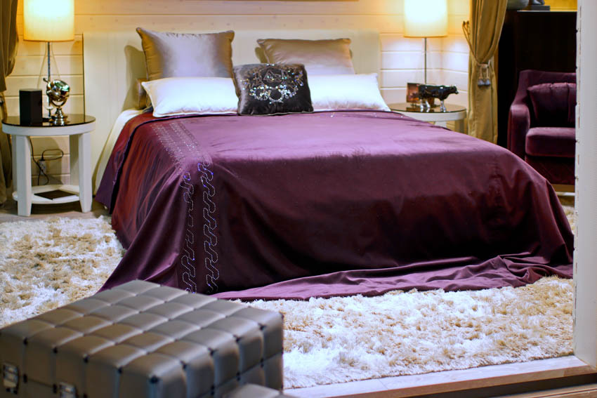 Bedroom with purple silk bed sheet rug lamp pillows