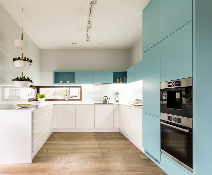 Blue and white cabinets in modern kitchen interior with wooden floor and ceiling lights